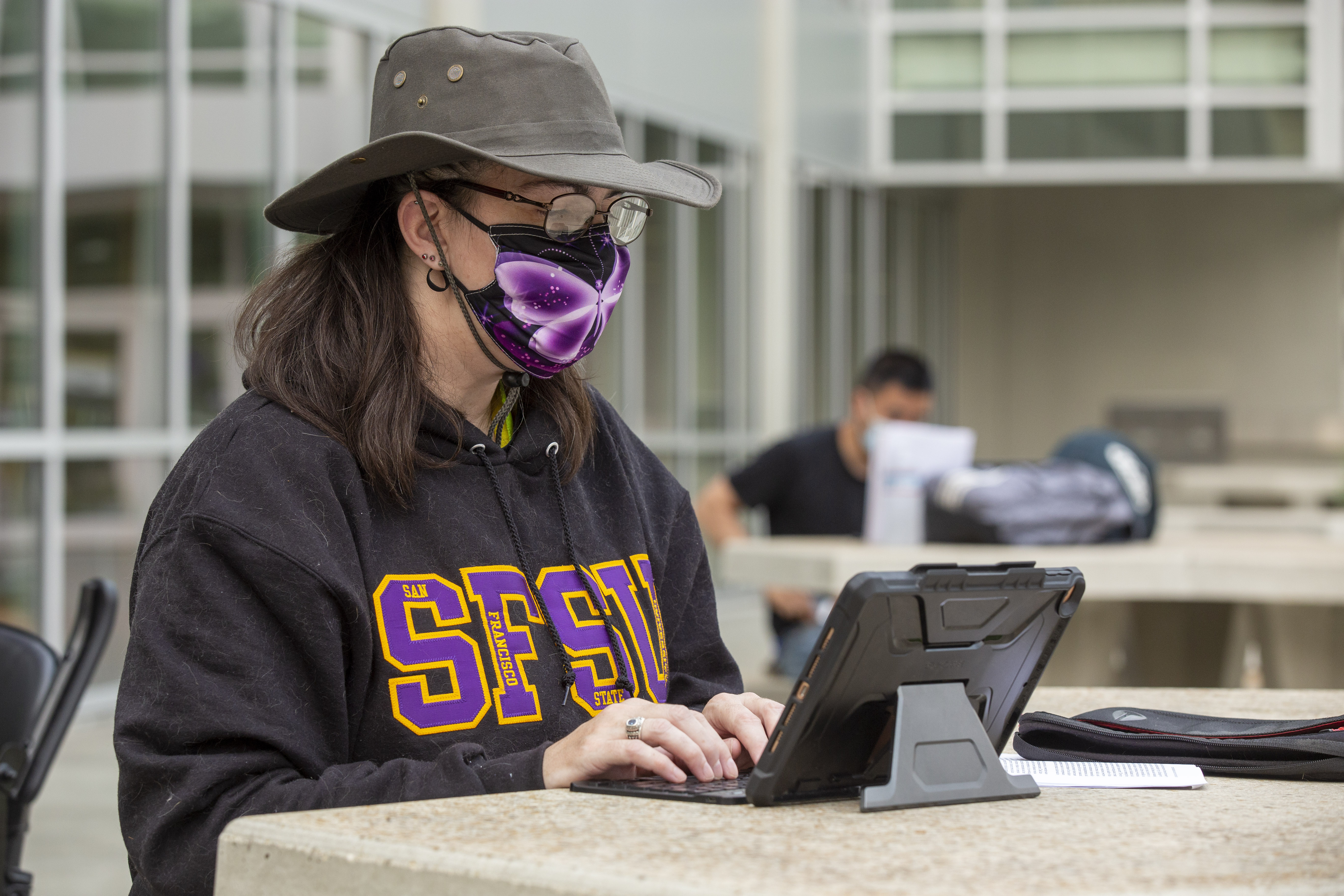 Student with SFSU hoodie working on a laptop